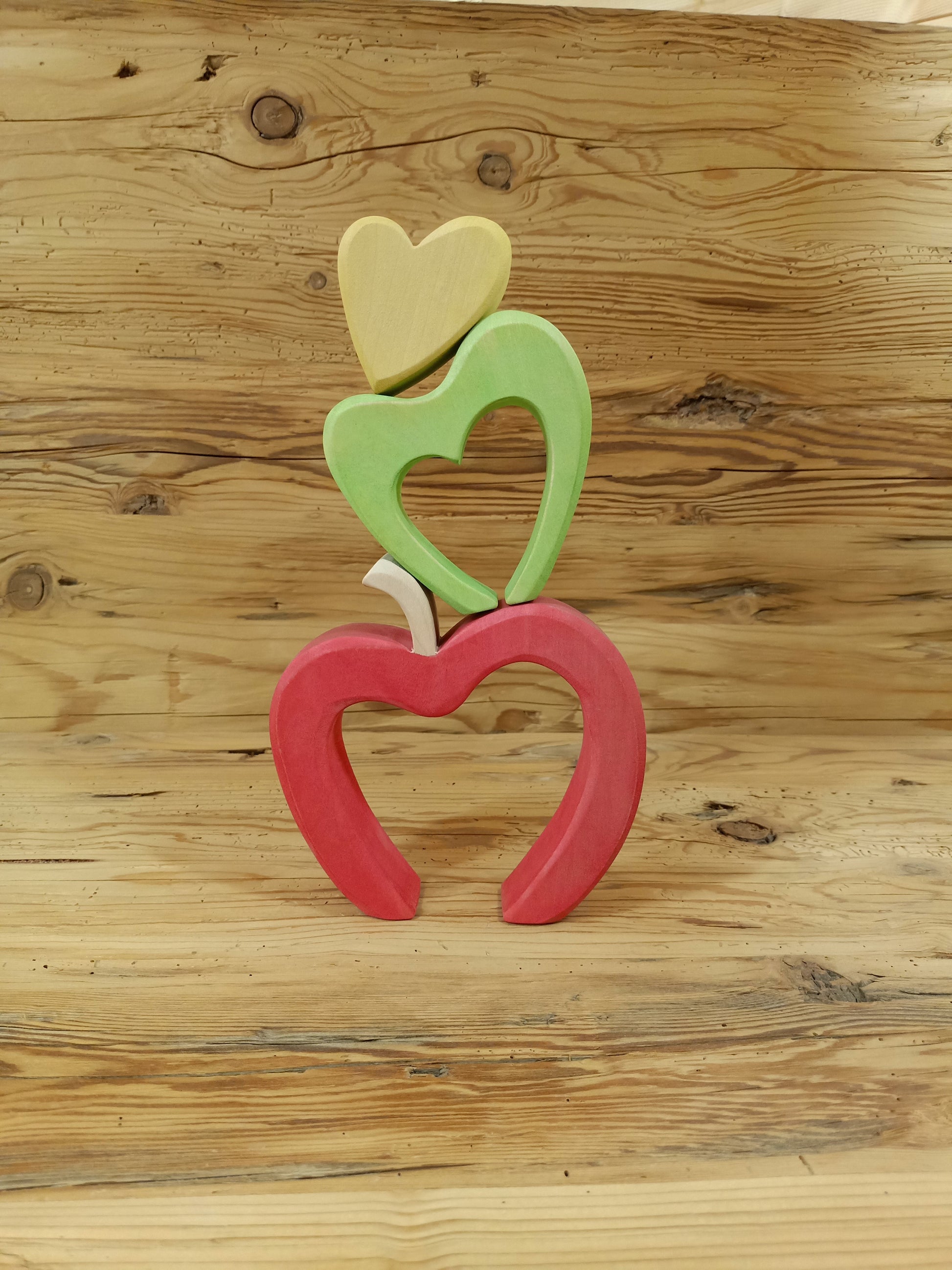 Handgefertigter Südtiroler Herzapfel aus Holz von NaturWunderWerk – zauberhaftes Herzstapelspiel in den Farben der Südtiroler Apfelsorten Royal Gala, Granny Smith und Golden Delicious für Kinder und Erwachsene.